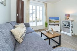 a living room with a blue couch and a tv at Söl'ring Hüs "Rantumer Idyll" in Rantum