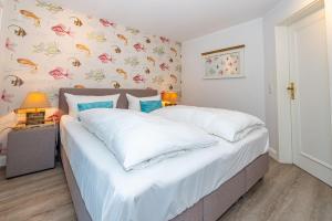 a bedroom with a large bed with white sheets at Söl'ring Hüs "Rantumer Idyll" in Rantum