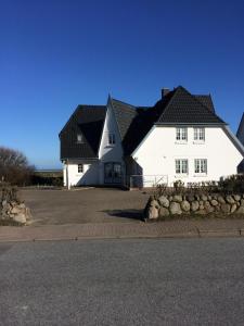 a large white house with a black roof at Warfthüs, App 1 in Rantum +3 photos