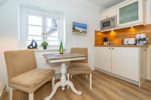 a kitchen with a table and two chairs and a counter at Söl'ring Hüs "kleiner traum rantum" in Rantum