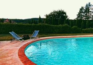 two blue chairs sitting next to a swimming pool at Camugnano farm in Rapolano Terme