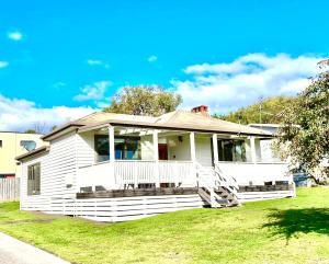 a white house with a porch on a lawn at Ocean Road Holiday House in Marengo