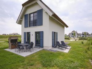 a white house with black shutters and a table and chairs at Reetland am Meer - Superior Reetdachvilla mit 2 Schlafzimmern F25 in Dranske