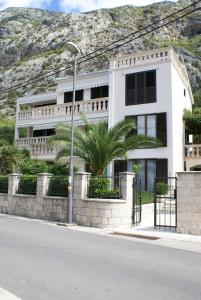 a white building with a palm tree in front of a mountain at Apartments Radulovic in Kotor