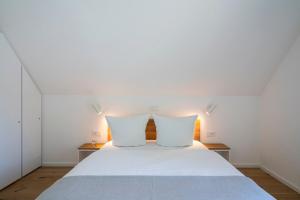a bedroom with a white bed with two pillows at Haus Riga in Prerow