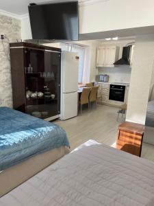 a bedroom with a bed and a kitchen with a refrigerator at Samal-2 Hotel in Almaty