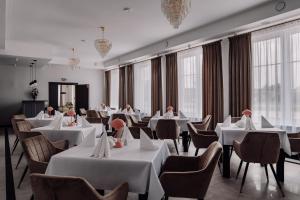 a restaurant with white tables and chairs and windows at Hotel Słowik in Kielce