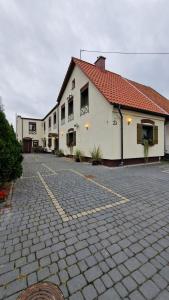 a white building with a red roof on a street at L&B House in Malbork