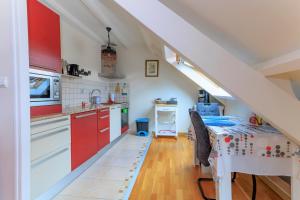a kitchen with red cabinets and a table with a table cloth at LE NID DES MOUETTES in Cherbourg en Cotentin