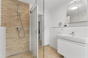 a white bathroom with a shower and a sink at Schonergang Greetje Oog in Krummhörn