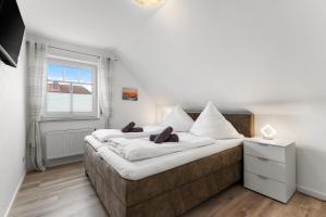 a bedroom with a large bed with white sheets and a window at Schonergang Greetje Oog in Krummhörn