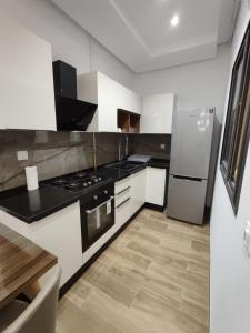 una cocina con estufa y refrigerador en Coquet appartement avec piscine à 10min de l'aéroport Tunis - family only, en La Soukra