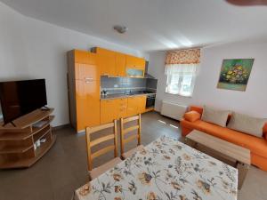 a living room with an orange couch and a kitchen at Apartments Palit in Rab