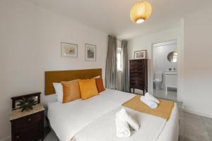 una camera da letto con un grande letto bianco con cuscini arancioni di Casa do Alecrim a Óbidos
