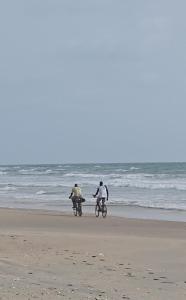 two people riding bikes on the beach at Eden Garden Tujereng gambia in Sanchaba +2 photos