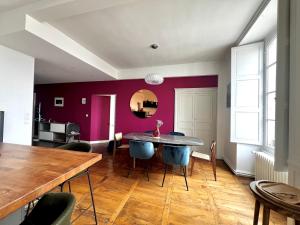 a dining room with a table and a purple wall at L'Opéra, hyper centre de Rennes in Rennes