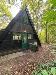 a black house with a green door in the woods at Chalet 23 in Durbuy