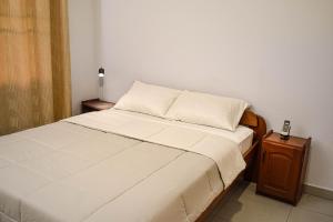a small bedroom with a bed and a night stand at Nazubs Suites in Paramaribo