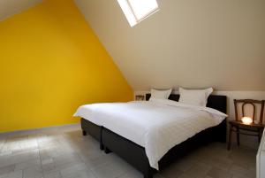 een slaapkamer met een groot bed met gele muren bij Back2Front in Boezinge