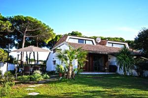 a white house with an umbrella in the yard at Villa Giannella in Orbetello