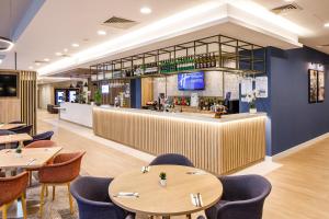 a restaurant with wooden tables and chairs and a bar at Holiday Inn Express London - ExCel, an IHG Hotel in London