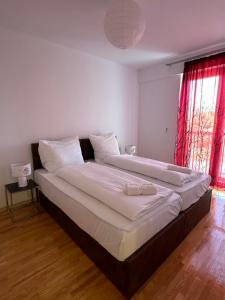 a large bed in a white room with red curtains at Design Prishtina Apartment 1 in Pristina