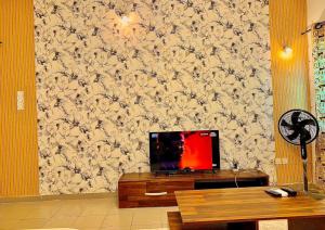 sala de estar con TV en una pared de flores en Appartement Jito, en Cotonou