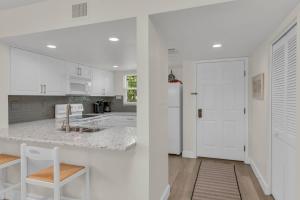 a kitchen with white cabinets and a white door at Short Walk to Beach Access I Coastal 2 Bed Essex in Henry Key