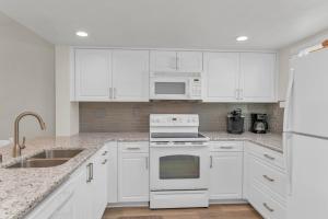 a kitchen with white cabinets and white appliances at Short Walk to Beach Access I Coastal 2 Bed Essex in Henry Key +14 photos