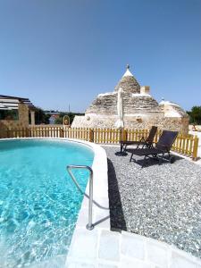 a swimming pool with two chairs and an umbrella at Trullo Famiglia in Putignano