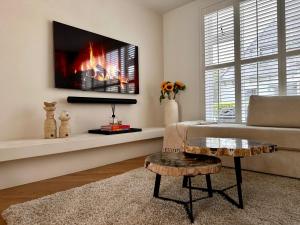 ザントフォールトにあるDutch Grand Prix Beach Houseのソファと壁掛けテレビのあるリビングルーム