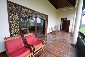 a living room with two chairs and a balcony at Uma Capung Mas Cottage in Ubud