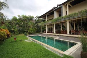 a house with a swimming pool in front of it at Uma Capung Mas Cottage in Ubud