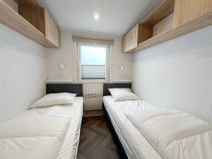 two beds in a room with a window at Chalet 503a op Recreatiepark De Wielen in Sint Maarten +14 photos