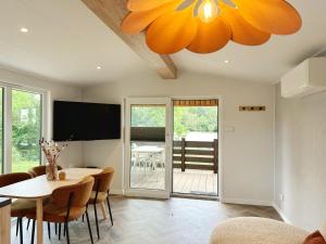 a dining room with a table and a tv at Chalet 503a op Recreatiepark De Wielen in Sint Maarten