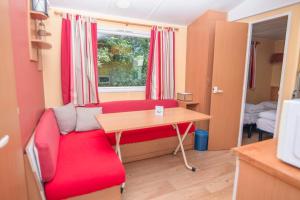 a living room with a red couch and a table at Camping Onlycamp La Colombière in Pesmes
