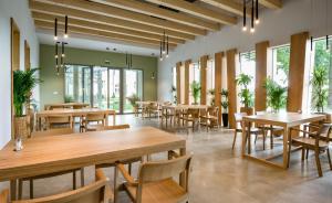 a restaurant with wooden tables and chairs and windows at Geszt, Tisza-kastély, Arany János Vendégház és Étterem in Geszt