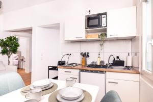 una cocina con armarios blancos y una mesa con platos en Design Suite! Familie - Küche - Zentral, en Wuppertal