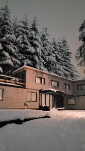 a house covered in snow with trees in the background at Pueblo Patagonia in Villa La Angostura