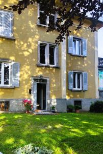 a yellow house with a lawn in front of it at Villa Alma, Lake Como Bed&Breathe in San Fedele Intelvi