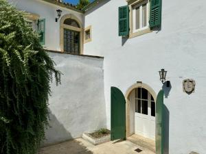 a white building with a green door and window at Charming Villa for nature lovers in Theotoky Estate Vineyard and olive mill in Corfu