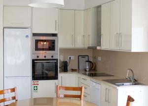 a kitchen with white cabinets and a table and chairs at mar(y)ar alojamento local in A dos Cunhados