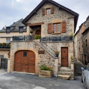 a stone house with two garage doors and a staircase at Gite Chez Laurette 12 in Sainte-Eulalie-dʼOlt