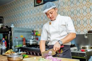 een chef-kok die eten bereidt op een snijplank in een keuken bij 520 hôtel & Résidence in Abidjan