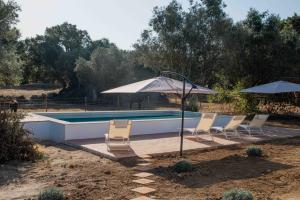 a swimming pool with chairs and umbrellas at Casa da Bolota T1 - Monte do Serrado de Baixo in Évora