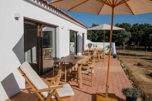 a patio with a wooden table and chairs and an umbrella at Casa da Bolota T1 - Monte do Serrado de Baixo in Évora