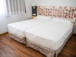 a bedroom with a large bed with white sheets at Hotel Plaza Palmeras in Puerto del Carmen +19 photos