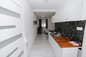 uma cozinha com armários brancos e bancadas de mármore preto em Hardi 1 em Trebinje mais 1 fotografia