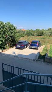 two cars parked in a parking lot next to a road at STYLISH STUDIO APARTMENT BURE in Murter