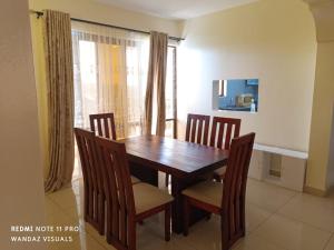 a dining room with a wooden table and chairs at Elegant rooms and apartment with pool in Nyali in Mombasa